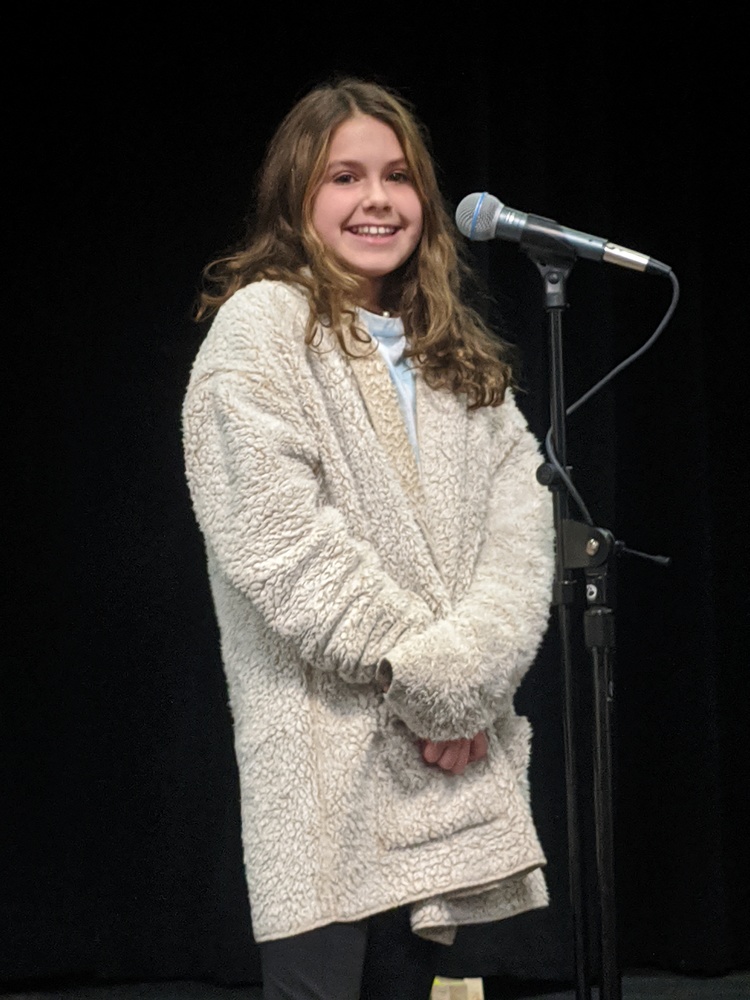 Student standing in front of microphone as the Spelling Bee winner